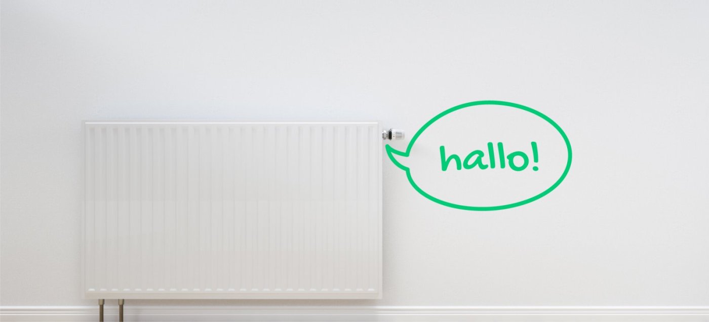 Weiße Heizung an Wand, daneben grüne Sprechblase mit dem Wort „hallo!“x